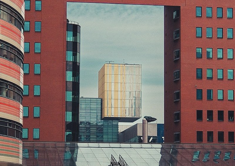 Eine große rechteckige Öffnung in einem roten Backsteingebäude rahmt den Blick auf einen goldfarbenen Gebäudekubus.