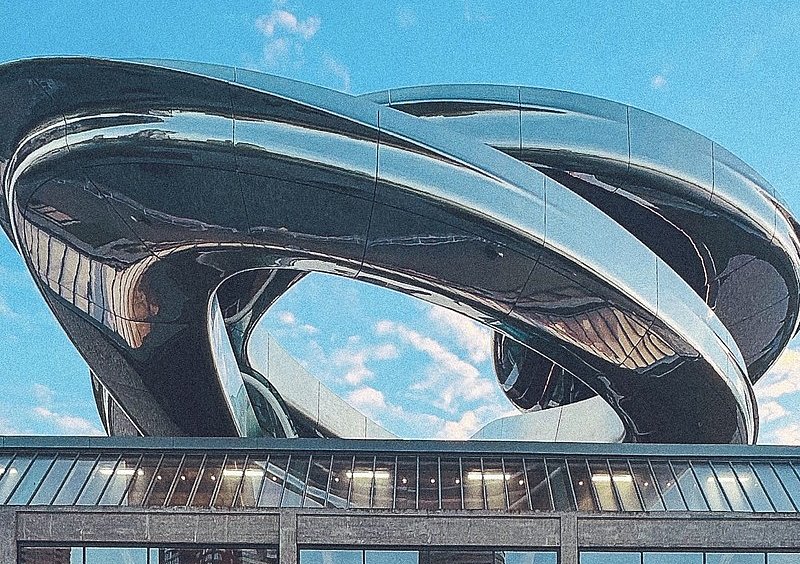 ie silbern glänzende, spiralförmige Dachkonstruktion des Kunstmuseums Fenix vor blauem Himmel.