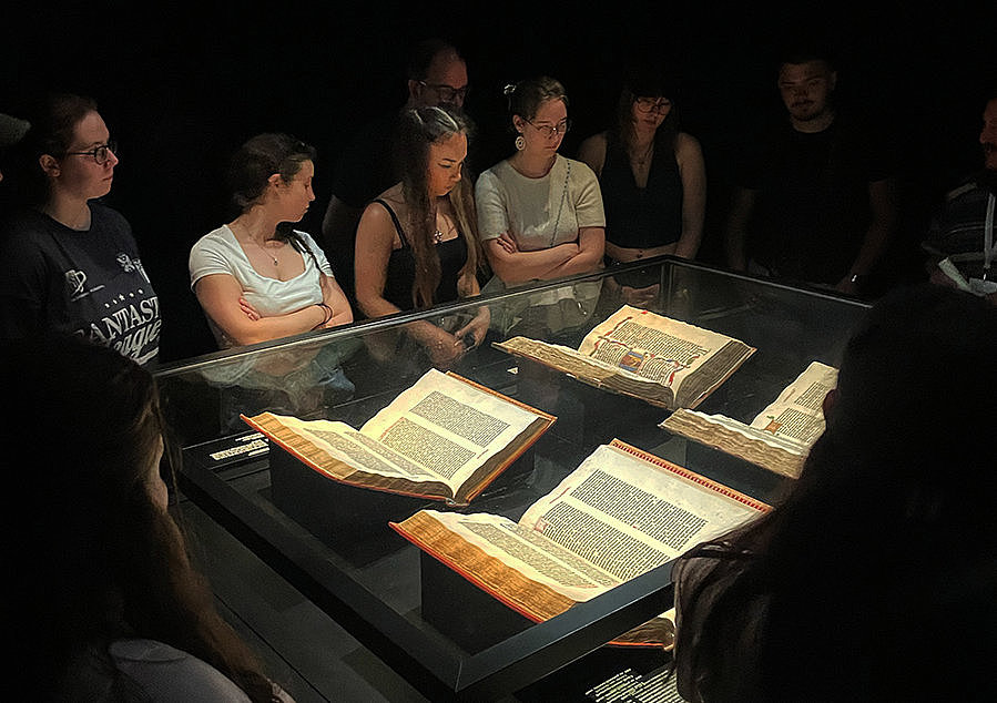 Auszubildende betrachten in einem abgedunkelten Raum originale Gutenberg-Bibeln